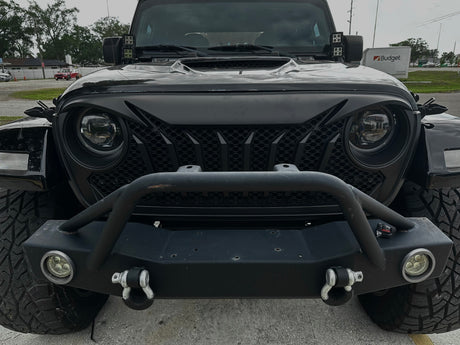 Front view of a black Jeep with additional lights and bumper on a road.