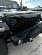 Close-up of a black Jeep vehicle's front grille and headlight. Jeep Wrangler JL/ JLU and Gladiator.